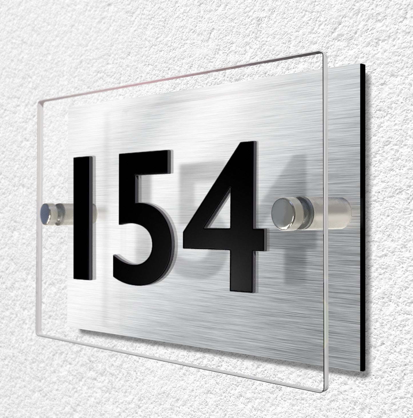 House sign constructed of two layers of material. Brushed aluminium and clear acrylic materials are held separate by stainless steel stand-ff fixings. House number is made from 3mm thick black acrylic and bonded to the clear acrylic for a raised lettering effect.