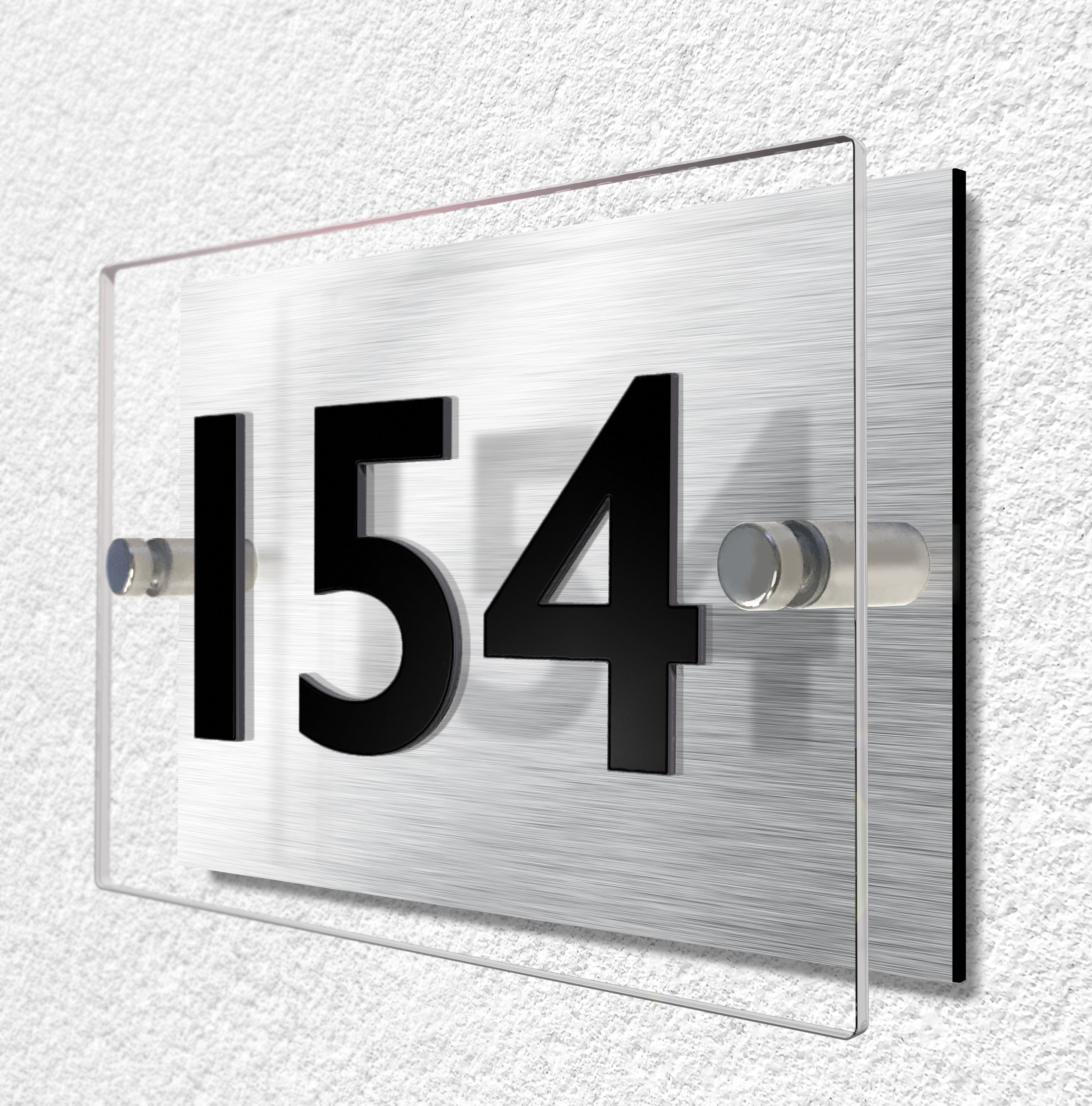 House sign constructed of two layers of material. Brushed aluminium and clear acrylic materials are held separate by stainless steel stand-ff fixings. House number is made from 3mm thick black acrylic and bonded to the clear acrylic for a raised lettering effect.