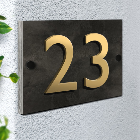 A wall mounted house sign. Constructed from 1cm thick honed slate with a smooth matt face. The number is made from Gold Acrylic and is professionally bonded to the surface.