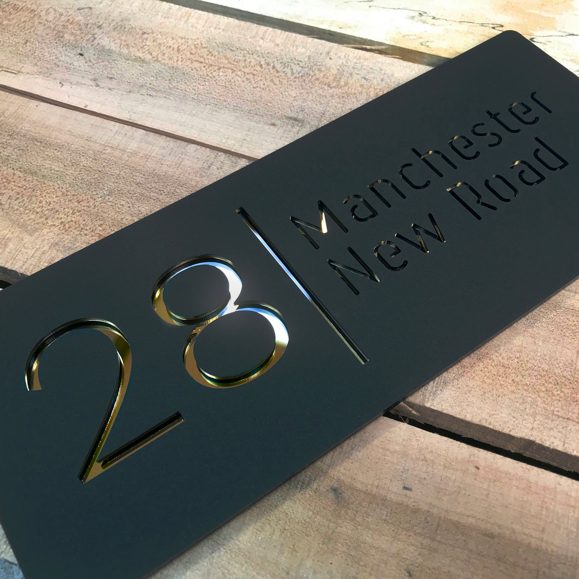 A house sign that displays the house number and street name. The sign is constructed from matt black acrylic and gold mirror for a stunning eye-catching effect.