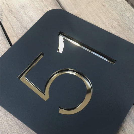 Video showing a Stellito house sign in different angles. As the camera moves and pans it reveals the reflective nature of the mirrored surface from which the numbers are made.