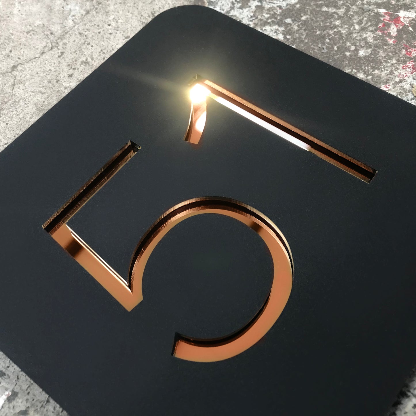 A Stellito acrylic house number sign with highly reflective Rose Gold mirror numbers.