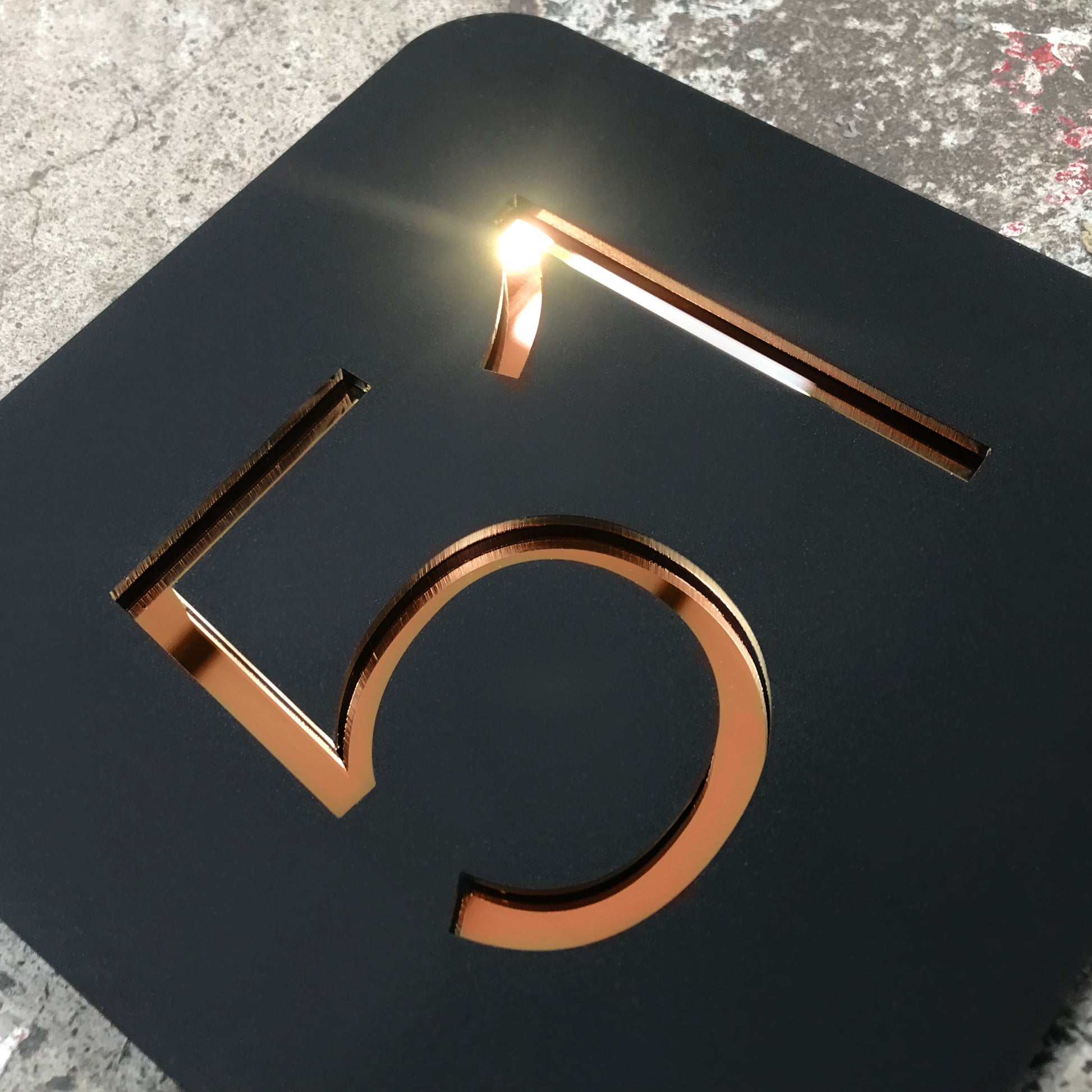 A Stellito acrylic house number sign with highly reflective Rose Gold mirror numbers.
