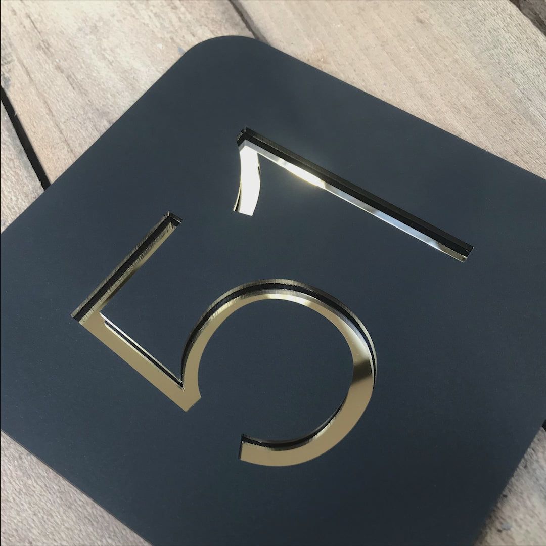 Video showing a Stellito house sign in different angles. As the camera moves and pans it reveals the reflective nature of the mirrored surface from which the numbers are made.